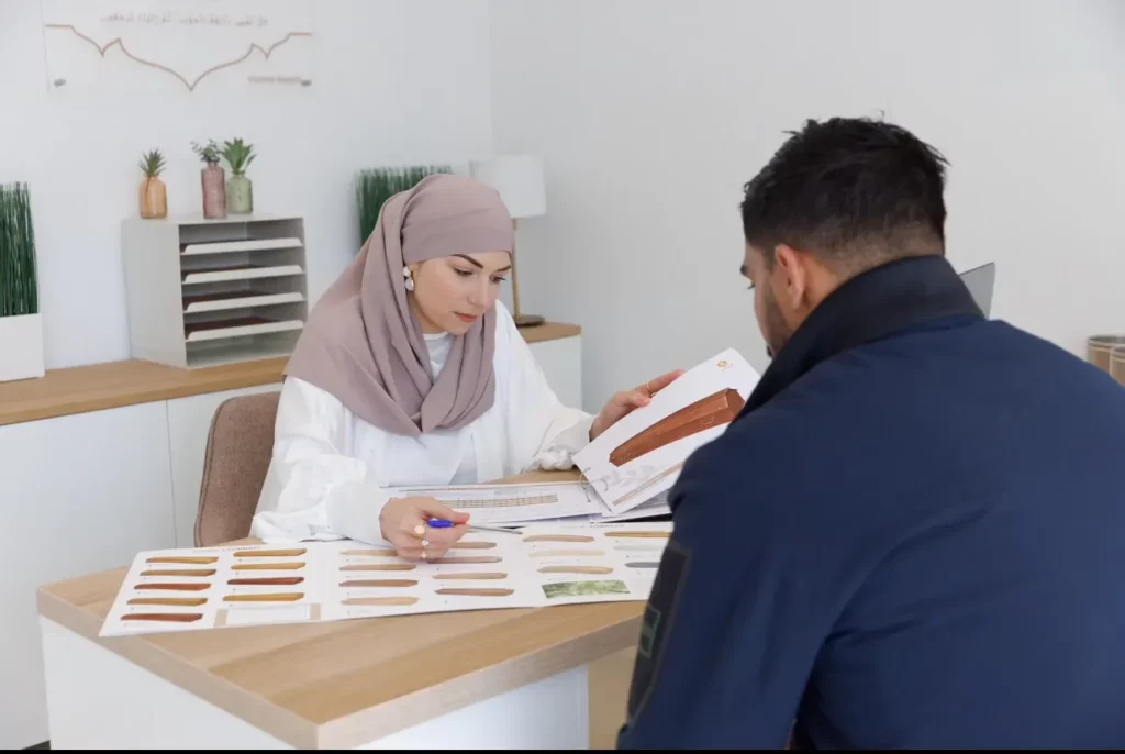 Conseillère funéraire présentant un catalogue de cercueils et finitions de bois à un client.