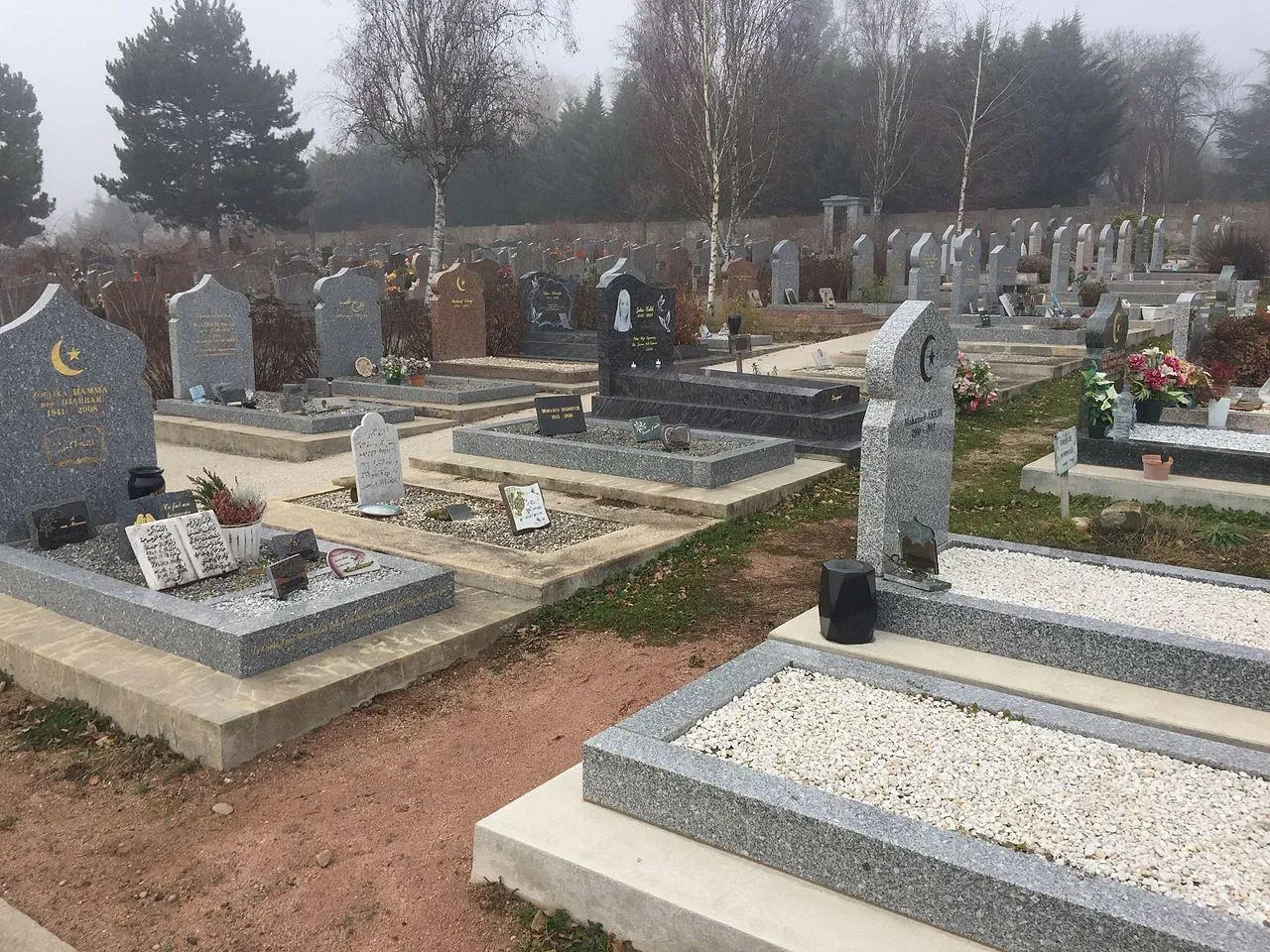 Carré musulman dans un cimetière avec tombes et stèles funéraires en granit.